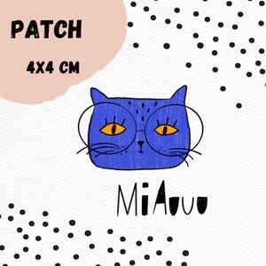 Könnte beinhalten: Blaue Katze mit runden Brillen und orangefarbenen Augen und dem Text "Miauu" in Schwarz. Das Bild ist ein 4x4 cm Patch.