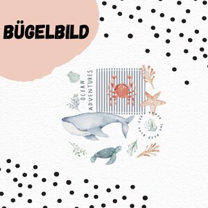 Op de afbeelding: Waterverf ontwerp met zeedieren zoals een walvis, krab, zeester en schildpad. Het ontwerp bevat de tekst "Ocean Adventures" en "The Blue Sea Under Deep". Het woord "BÜGELBILD" is ook aanwezig.