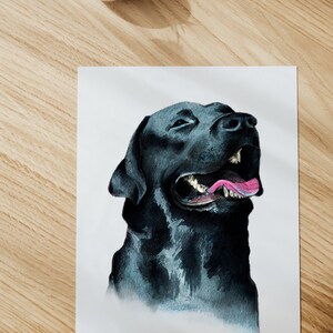 May include: A watercolor painting of a black Labrador Retriever with its mouth open and tongue sticking out. The dog is looking up and to the right. The painting is on a white background.