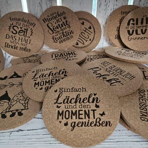 Könnte beinhalten: Eine Sammlung von Korkuntersetzern mit verschiedenen Sprüchen und Designs. Einige der Sprüche lauten: "Freundschaft ist das Seil, das alle Fäden zusammenhält", "Ein guter Mensch ist Sonnenschein, der alle zum Lächeln bringt", "Einfach lächeln und den Moment genießen", "Glück ist die Summe schöner Erinnerungen", "Sei glücklich, nicht perfekt", und "Was für ein wunderschöner Tag".