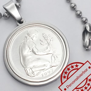 Könnte beinhalten: Eine silberne Halskette mit einem Anhänger, der eine deutsche 5-Deutsche-Mark-Münze aus dem Jahr 1992 mit einer Frau zeigt, die einen Baum pflanzt. Die Münze ist an einer silbernen Kette mit einem Karabinerhaken befestigt.