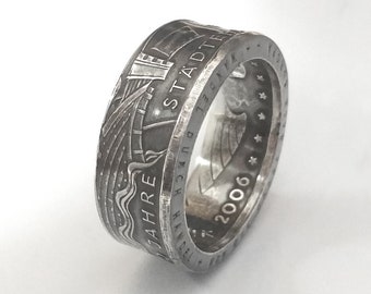 May include: A silver ring made from a 2006 German coin. The ring features a design of a ship and the text "STADT BREMERHAVEN 725 JAHRE".