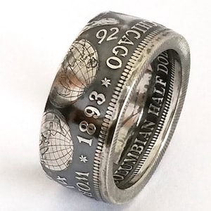 Könnte beinhalten: Ein silberner Ring, der aus einer 1893 Columbian Half Dollar-Münze gefertigt wurde. Der Ring zeigt das Originaldesign der Münze, einschließlich der Inschrift "Columbian Half Dollar" und dem Jahr "1893".