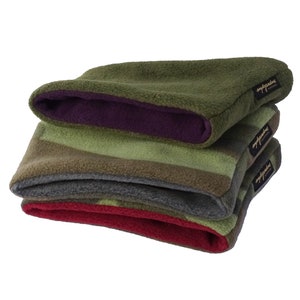 Könnte beinhalten: Ein Stapel von vier Fleece-Halstüchern in verschiedenen Farben. Das oberste Halstuch ist olivgrün mit einem violetten Innenfutter. Die anderen sind in Grün-, Grau- und Rottönen gestreift. Jedes Halstuch hat ein kleines schwarzes Etikett.