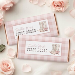 May include: Two pink and white gingham chocolate bar wrappers with a gold border. The wrappers feature a pair of pink and white cowboy boots with the text "Millie Mae's First Rodeo".