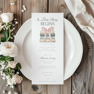May include: A bridal shower menu with a watercolor illustration of a stack of books tied with a pink ribbon. The menu includes starters, main course, and dessert options. The text reads "A Love Story Begins" and "Elizabeth's Bridal Shower".