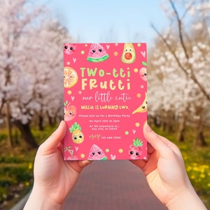 May include: A pink invitation card with a watercolor illustration of fruit with faces. The text on the card reads "Two-tti Frutti our little cutie Millie is turning two. Please join us for a Birthday Party On April 12th at 2pm At 123 anywhere st any city, st 12345 ngup 123-456-7890"