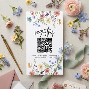 May include: A rectangular white registry card featuring a watercolor floral border with pink, blue, and yellow flowers. The card displays the word registry in black script, a black QR code, and the text Scan the QR code to connect to our online registry.