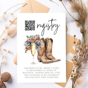 Puede incluir: Una tarjeta de invitación blanca con la palabra "registry" en escritura cursiva. La tarjeta presenta una ilustración de acuarela de botas de vaquero, una copa de champán y un arreglo floral. La tarjeta incluye un código QR y texto.