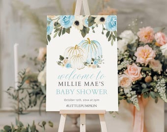 Puede incluir: Un cartel de bienvenida para una baby shower de color blanco y azul con un diseño floral y calabazas. El cartel dice "Bienvenido a Millie Mae's Baby Shower" e incluye la fecha "12 de octubre de 20xx a las 2 pm" y el hashtag "#LittlePumpkin".