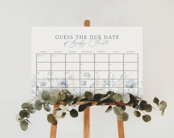 May include: A rectangular sign titled GUESS THE DUE DATE of Baby Smith featuring a monthly calendar grid with black lines, dates, and a soft blue floral watercolor illustration along the bottom edge, displayed on a wooden easel stand.