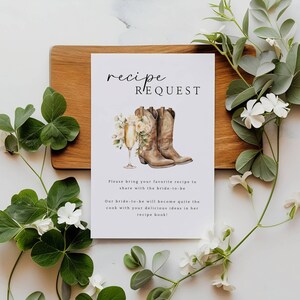 May include: A white card with the text "recipe request" in black script font. The card features a watercolor illustration of two brown cowboy boots with a glass of champagne and flowers.