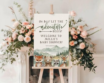 Peut inclure: Une pancarte de bienvenue pour une fête prénatale sur le thème de la forêt. La pancarte présente une illustration aquarelle d'une chaîne de montagnes, d'arbres et d'animaux, dont un renard, un ours, un raton laveur et un cerf. Le texte sur la pancarte indique "Oh Boy! Let the adventure begin! Welcome to Millie's Baby Shower!"