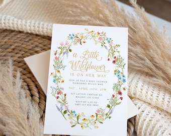 Può includere: Un biglietto d'invito rettangolare bianco per baby shower con una ghirlanda di fiori di campo ad acquerello che circonda il testo: a Little Wildflower IS ON HER WAY, JOIN US FOR A BABY SHOWER HONORING MILLIE MAE, SAT. APRIL 12TH, 2PM, 327 LATIGO CANYON RD. MALIBU, CA 12345, RSVP BY 3.25 TO AMY 123.456.7890.