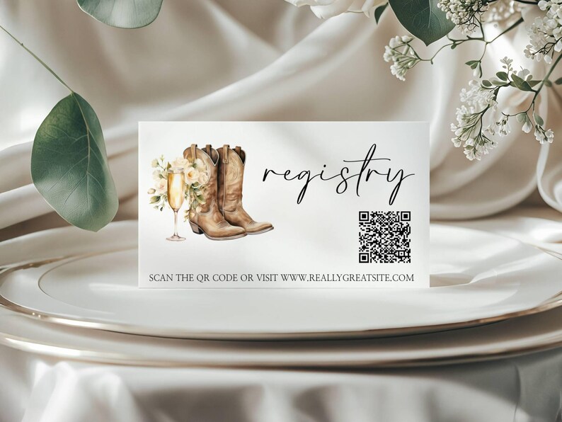 K&ouml;nnte beinhalten: Eine wei&szlig;e Karte mit dem Wort &bdquo;registry&ldquo; in eleganter Schrift. Die Karte zeigt Aquarellillustrationen von Cowboy-Stiefeln, Champagner und Blumen. Ein QR-Code und eine Website-Adresse sind ebenfalls enthalten.