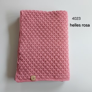 May include: A rectangular knitted blanket in a dusty pink color featuring a raised diamond texture pattern. A small square tan label with a bee icon is attached to the bottom left corner. The text 4023 helles rosa is printed in black.