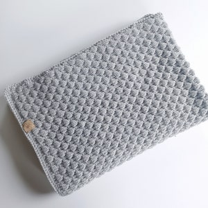 以下が含まれることがあります： グレーのダイヤモンド模様の編み地のベビーブランケット