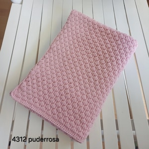 May include: A rectangular, light pink knitted blanket featuring a consistent, raised honeycomb or bubble texture pattern across the entire surface. The edges are finished with a simple, flat knit border. The text 4312 puderrosa is visible.