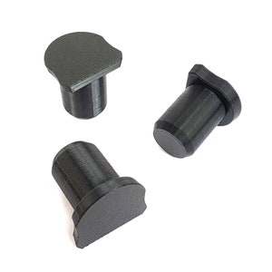 Könnte beinhalten: Drei schwarze, zylindrische Objekte mit flacher, halbkreisförmiger Oberseite. Die Objekte scheinen aus einem strukturierten, matten Material zu bestehen. Das Design ist einfach und funktional, mit Fokus auf Form und Gestalt.