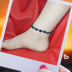 May include: A black beaded ankle bracelet with small round black beads and larger round black beads with a silver center.