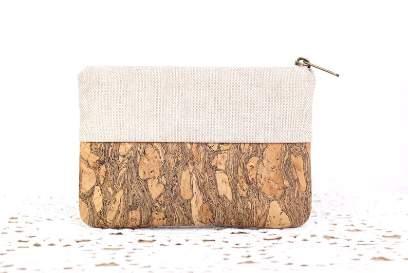 Puede incluir: Una peque&ntilde;a bolsa con cremallera con una parte superior de lino beige y una parte inferior de corcho. El corcho tiene un patr&oacute;n de m&aacute;rmol marr&oacute;n y negro natural.