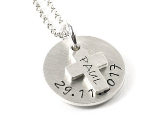Puede incluir: Collar de plata con un colgante redondo que presenta una cruz con el nombre "PAUL" y la fecha "29.7.17" grabada.
