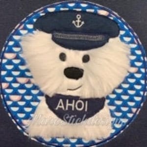 May include: White plush dog wearing a blue sailor hat with an anchor on top and a blue bandana with the word "AHOI" on it. The dog is surrounded by a blue and white pattern of half circles.