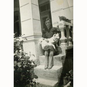 Signora sorridente con il suo cane sui gradini di casa sua. Grecia probabilmente anni '40. Foto d'epoca [53950]