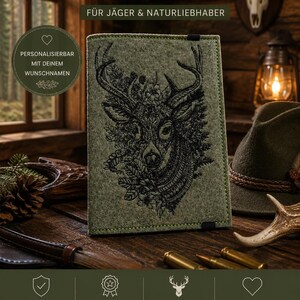 Könnte beinhalten: Grüner Filz-Jagdscheinhülle mit schwarzem Hirschkopf-Design. Der Text auf der Hülle lautet "JAGDSCHEINHÜLLE" und "UD JAGD PREMIUM". Personalisierbar, für Jäger und Naturliebhaber.