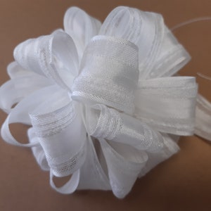 Op de afbeelding: Een witte satijnen strik met een textuurpatroon. De strik is gebonden in een grote, pluche vorm.