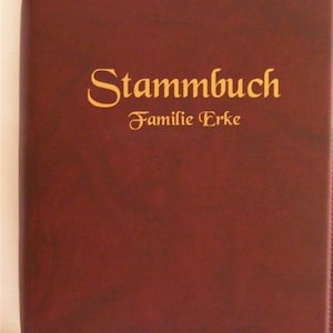 May include: A burgundy leather-bound book with gold lettering that reads "Stammbuch Familie Erke".