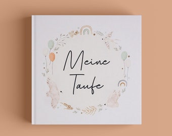 May include: A white book with a watercolor illustration of a wreath with birds, rainbows, and balloons. The text "Meine Taufe" is written in black cursive.