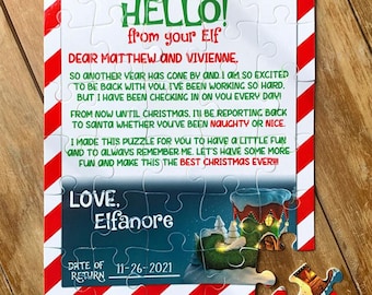 Op de afbeelding: Een rood-wit gestreepte puzzel met een brief van een elf aan Matthew en Vivienne. De brief zegt "Hallo! van je elf" en "Liefs, Elfanore". De puzzel heeft een afbeelding van een kerst elf in een huis met een retourdatum van 11-26-2021.