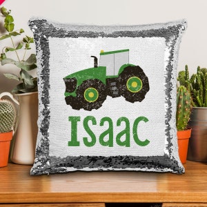 May include: A silver sequin pillow with a green and yellow tractor and the name "Isaac" printed on it.