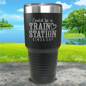 May include: Black stainless steel tumbler with a white inscription that reads "Could be a Train Station Kinda Day".