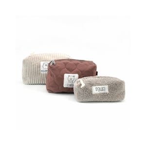 Könnte beinhalten: Drei Reißverschlusstaschen in verschiedenen Texturen und Farben. Die beige Tasche hat eine Kordstruktur und ein Etikett mit der Aufschrift Maxim. Die malvenfarbene Tasche ist gesteppt und trägt ein Bären-Etikett mit dem Namen Luisa. Die graue Tasche ist flauschig und mit Paula beschriftet.