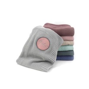 Könnte beinhalten: Ein Set aus drei Keramikbechern mit gesprenkelter, matter Oberfläche. Die Becher sind in Creme-, Hellgrau- und Dunkelgrautönen gehalten. Jeder Becher hat ein schlichtes, modernes Design und einen abgerundeten Henkel.