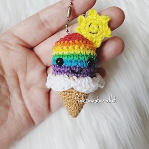 Può includere: Portachiavi a forma di cono gelato all'uncinetto arcobaleno con un ciondolo sole sorridente. Il cono gelato è realizzato con una varietà di colori, tra cui rosso, arancione, giallo, verde, blu e viola. Il ciondolo sole è giallo con un viso sorridente.