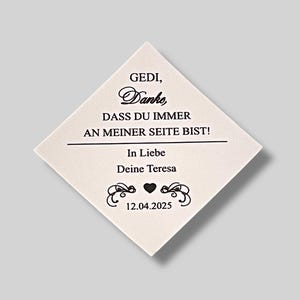 Könnte beinhalten: Eine weiße, rautenförmige Karte mit schwarzem Text, der "GEDI, Danke, DASS DU IMMER AN MEINER SEITE BIST! In Liebe Deine Teresa 12.04.2025" lautet. Die Karte hat ein schwarzes Herz und dekorative Schnörkel.
