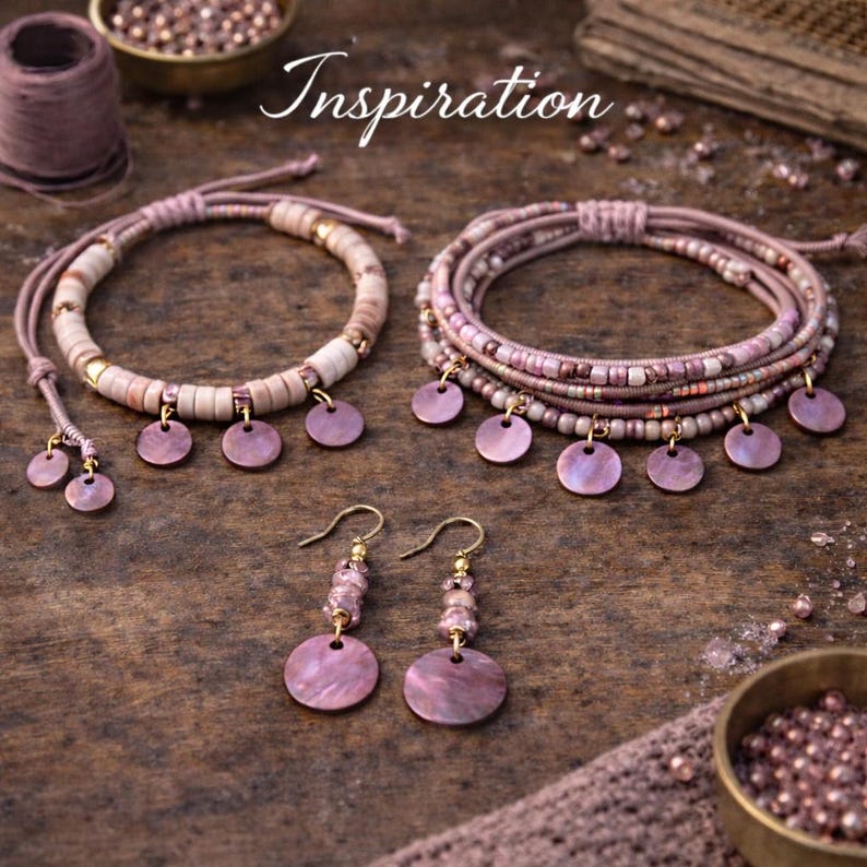 Op de afbeelding: Handgemaakte sieradenset met armbanden en oorbellen. De armbanden combineren kralen en ronde, roze schelpachtige bedels. De oorbellen hebben een vergelijkbaar ontwerp, met roze bedels en goudkleurige haken. Het woord "Inspiration" is cursief geschreven.