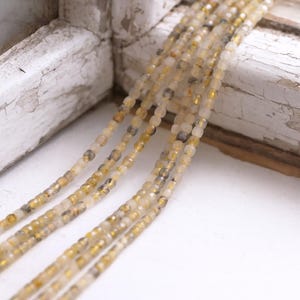 Koraliki kwarcu rutylowego w formie sześcianów o wymiarach 2,5 x 2,5 x 2,5 mm (ok. 140 koralików / ok. 38 cm długości)