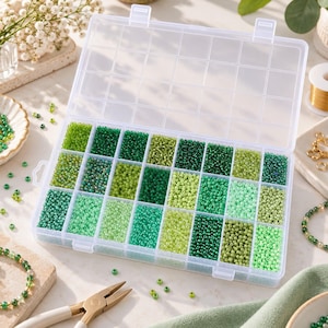 Op de afbeelding: Een doorzichtige plastic opbergdoos met vierentwintig rechthoekige vakjes gevuld met kleine glazen kraaltjes in diverse groentinten, variërend van licht limoen en mint tot diep bosgroen en smaragdgroen, gesorteerd op kleur.