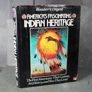 Puede incluir: Un libro de tapa dura titulado "America's Fascinating Indian Heritage" de Reader's Digest. La portada presenta una vibrante ilustración de un motivo nativo americano con un sol amarillo, un bisonte negro y plumas coloridas. El lomo del libro también muestra el título.