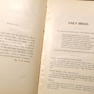 May include: Open book pages with text. The left page reads "PREFACE" and the right page reads "DAILY BREAD." Recipes for bread are listed, including ingredients and instructions. The book appears to be vintage, with aged paper and ink.