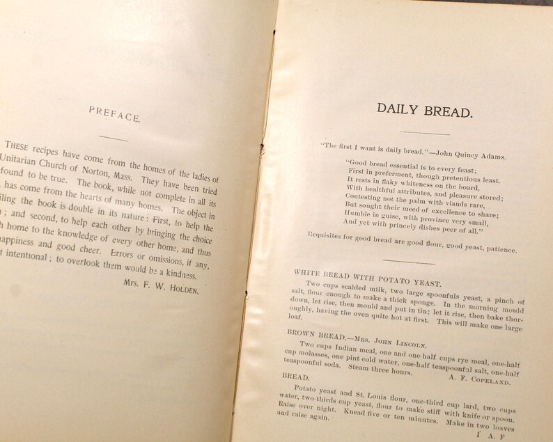 May include: Open book pages with text. The left page reads "PREFACE" and the right page reads "DAILY BREAD." Recipes for bread are listed, including ingredients and instructions. The book appears to be vintage, with aged paper and ink.