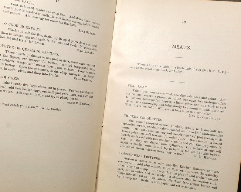 May include: Open book pages with vintage recipes for fish balls, oyster fritters, and veal loaf. The text is in black ink on aged paper, with headings like "MEATS" and author attributions.