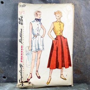 May include: Vintage Simplicity pattern envelope featuring illustrations of two women's outfits: a white romper and a yellow top with a red skirt. The envelope has text that reads "Simplicity Printed Pattern" and the price "25c".