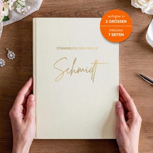 Könnte beinhalten: Ein cremefarbenes Familienstammbuch mit goldfarbenem Schriftzug "Stammbuch der Familie Schmidt". Das Buch wird von zwei Händen offen gehalten. Das Buch hat einen runden orangefarbenen Aufkleber mit der Aufschrift "verfügbar in 2 GRÖSSEN inklusive 7 SEITEN."