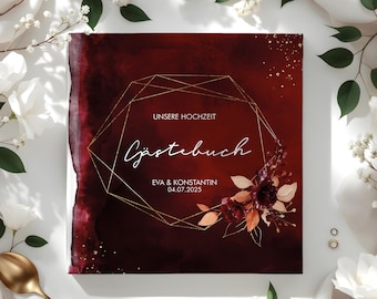 May include: A burgundy guest book with a gold geometric frame and floral accents. The text "Unsere Hochzeit" and "Gästebuch" are written in white. The names "Eva & Konstantin" and the date "04.07.2025" are also written in white.