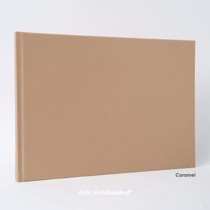 May include: A caramel-colored photo album with a fabric cover. The album is rectangular and closed, with a spine on the left side. The word "Caramel" is printed on the bottom right corner.